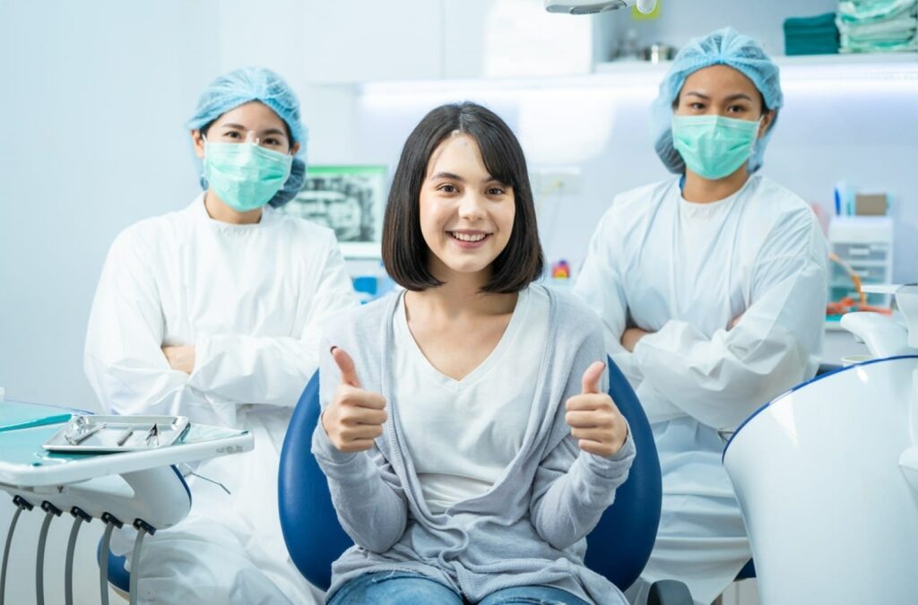 portrait-of-caucasian-girl-patient-smile-sitting-on-dental-chair-after-doctor-and-assistant