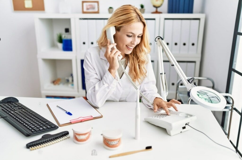 young-blonde-woman-wearing-dentist-uniform-speaking-on-the-phone-at-dental-clinic
